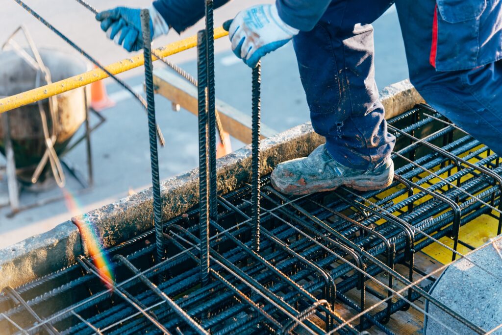 Construction worker using safety rules is working on a reinforced concrete slab preparing rebar